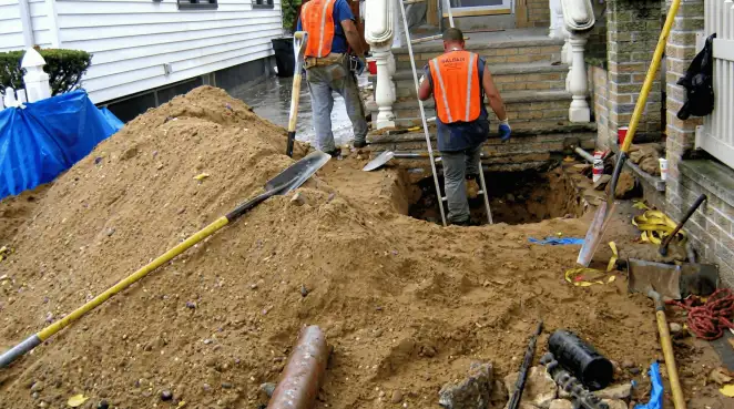 Contractors performing foundation protection and exterior drainage excavation near residential home steps in Hollywood, FL