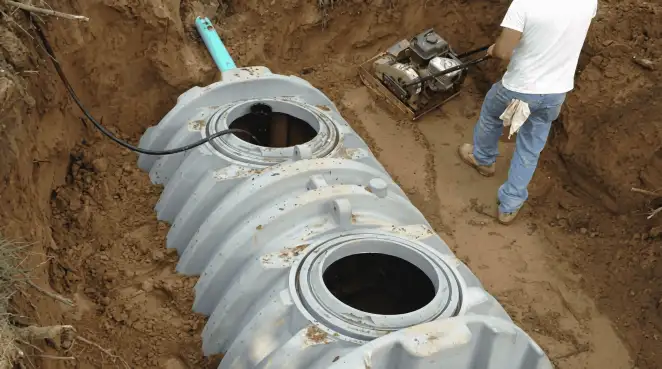 Septic tank installation showing a technician compacting soil around a new poly septic tank in an excavation pit in Hollywood, FL